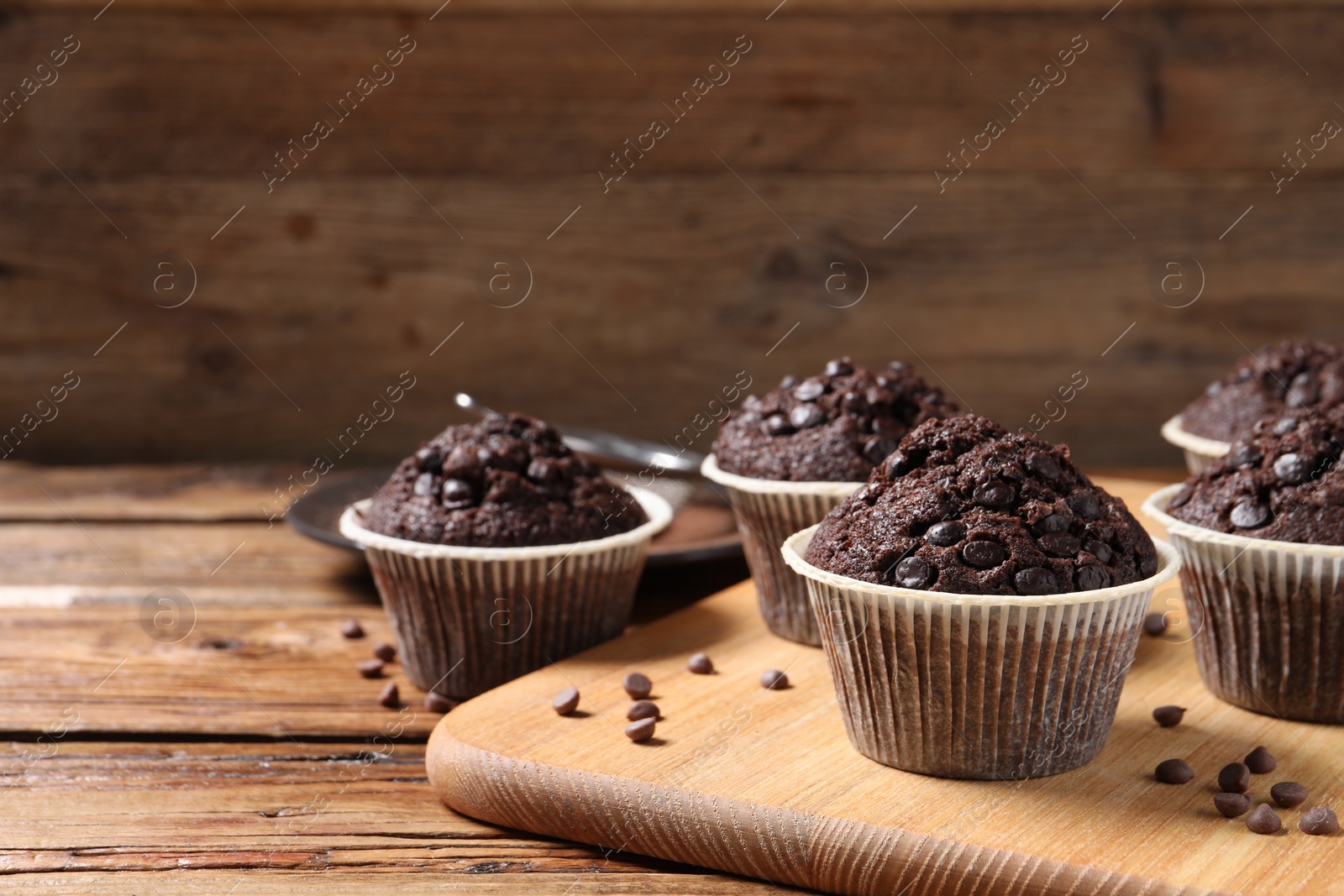 Photo of Tasty chocolate muffins on wooden table, closeup. Space for text