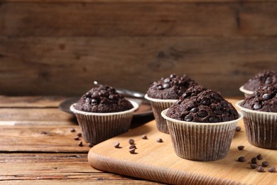 Photo of Tasty chocolate muffins on wooden table, closeup. Space for text