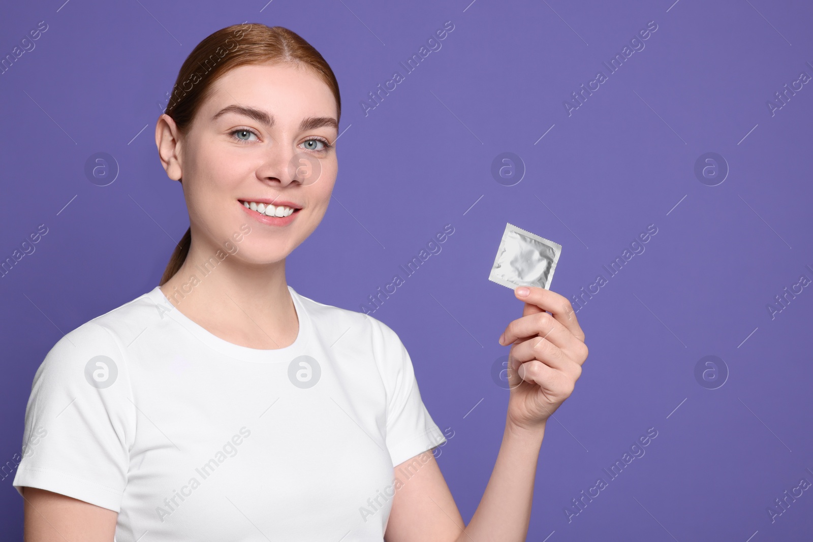 Photo of Woman holding condom on purple background, space for text. Safe sex