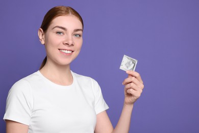 Photo of Woman holding condom on purple background, space for text. Safe sex