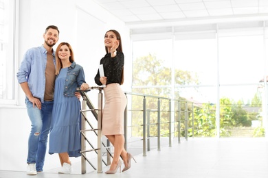 Photo of Female real estate agent showing new house to couple, indoors