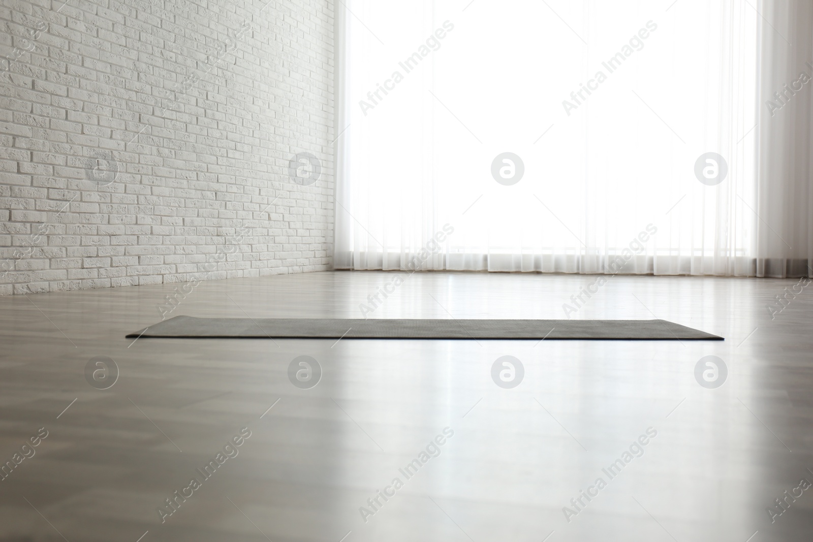 Photo of Unrolled grey yoga mat on floor in room