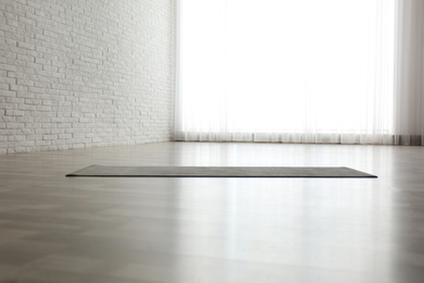 Photo of Unrolled grey yoga mat on floor in room