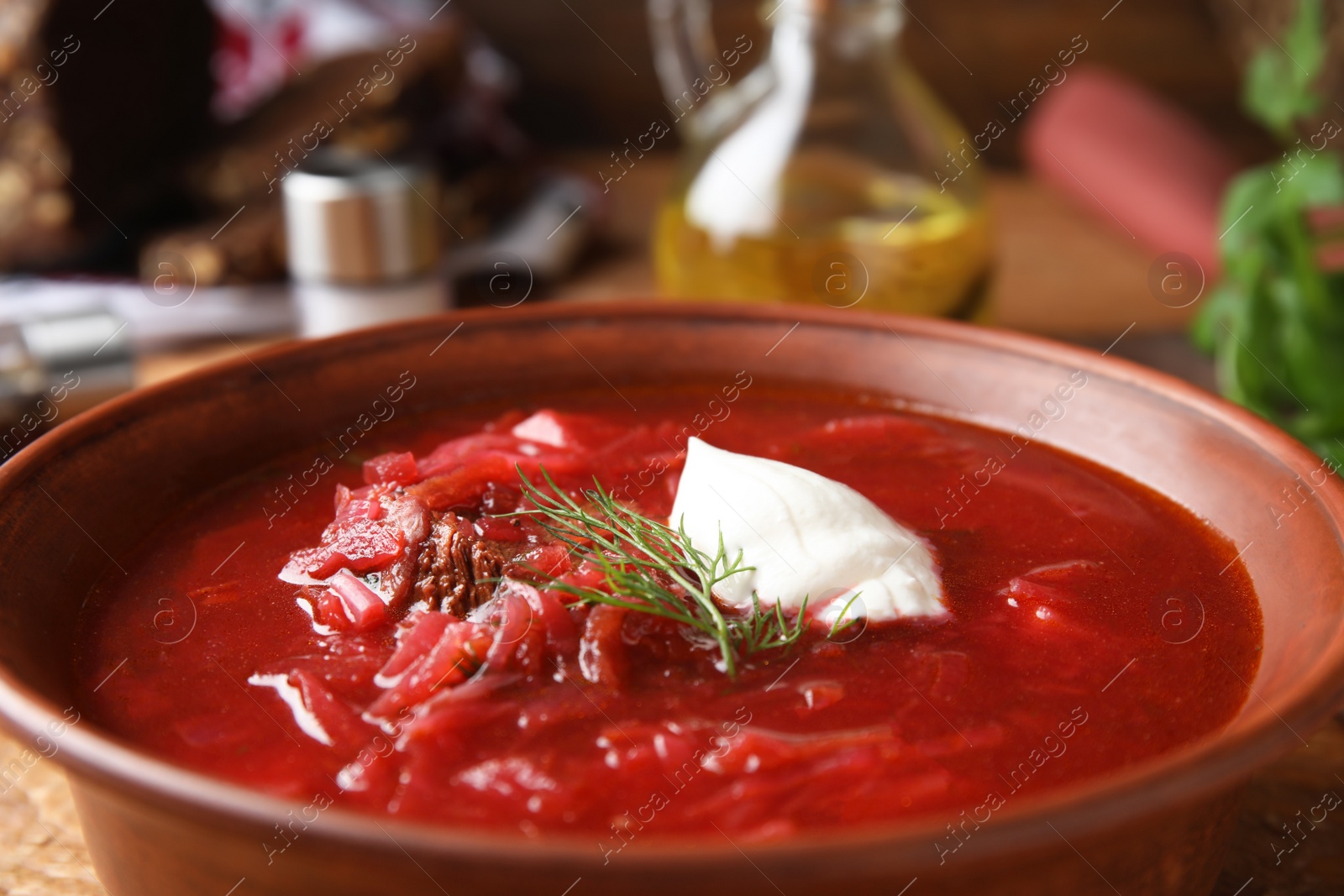 Photo of Clay bowl with Ukrainian borsch on table, closeup