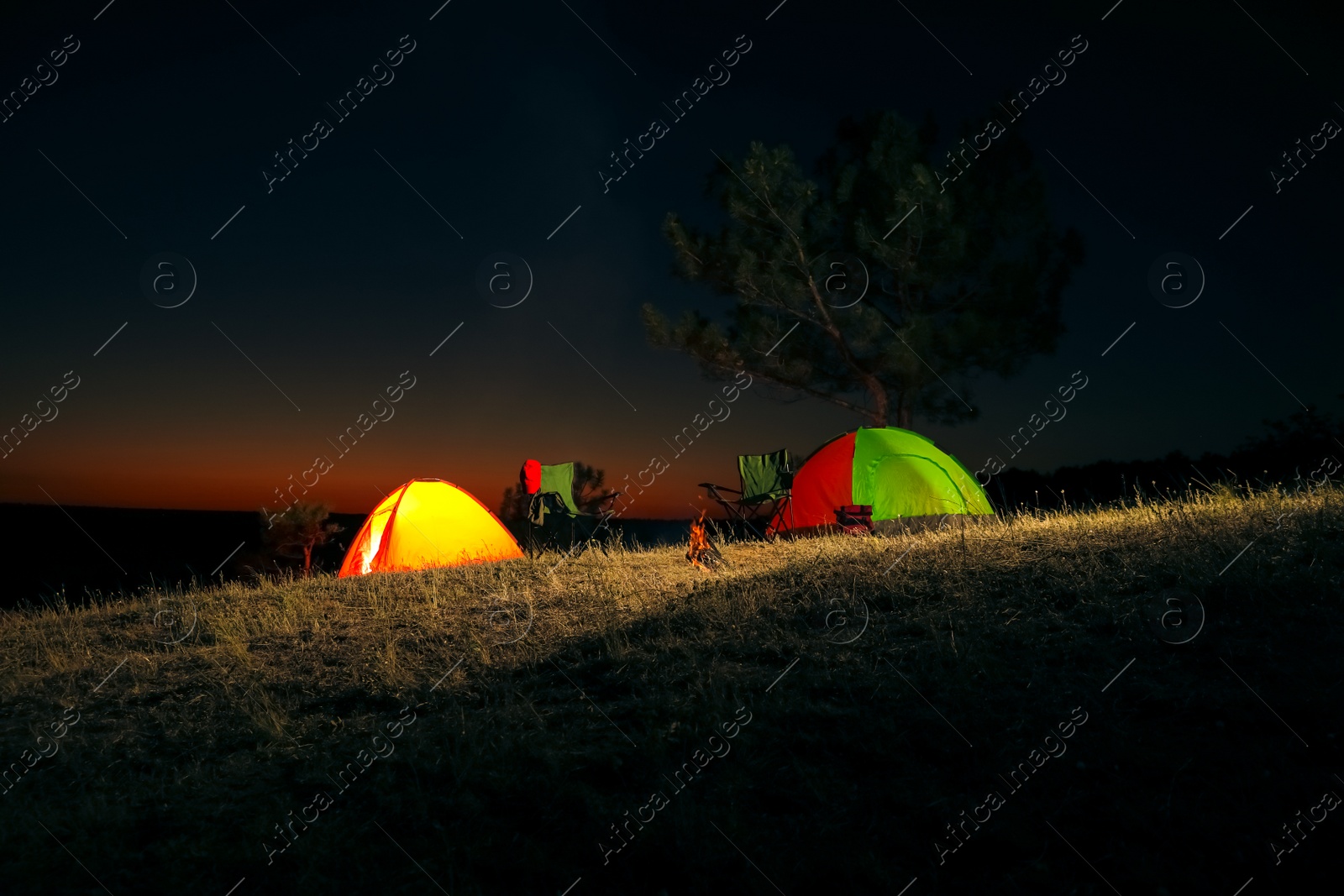 Photo of Camping tents and chairs in wilderness at night