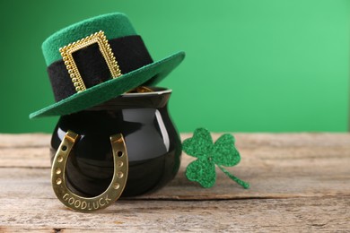 St. Patrick's day. Pot of gold with leprechaun hat, horseshoe and decorative clover leaf on wooden table. Space for text