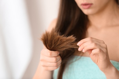 Photo of Woman with damaged hair on blurred background, closeup. Split ends