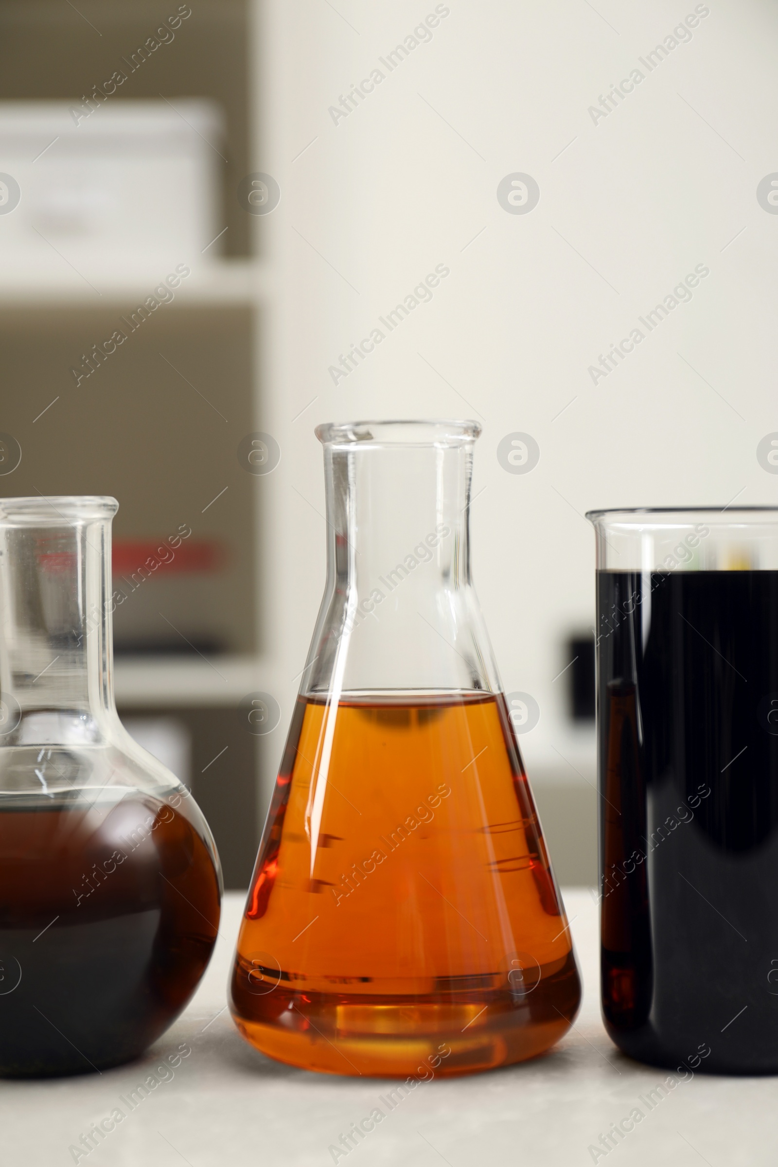 Photo of Flasks and beaker with different types of crude oil on light table