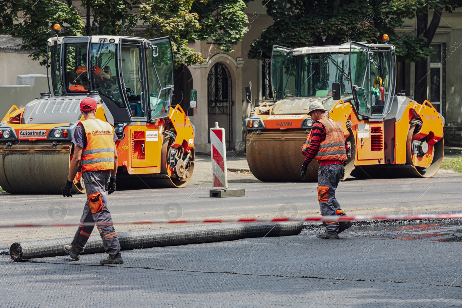 Photo of MYKOLAIV, UKRAINE - AUGUST 04, 2021: Workers with road repair machinery laying new asphalt