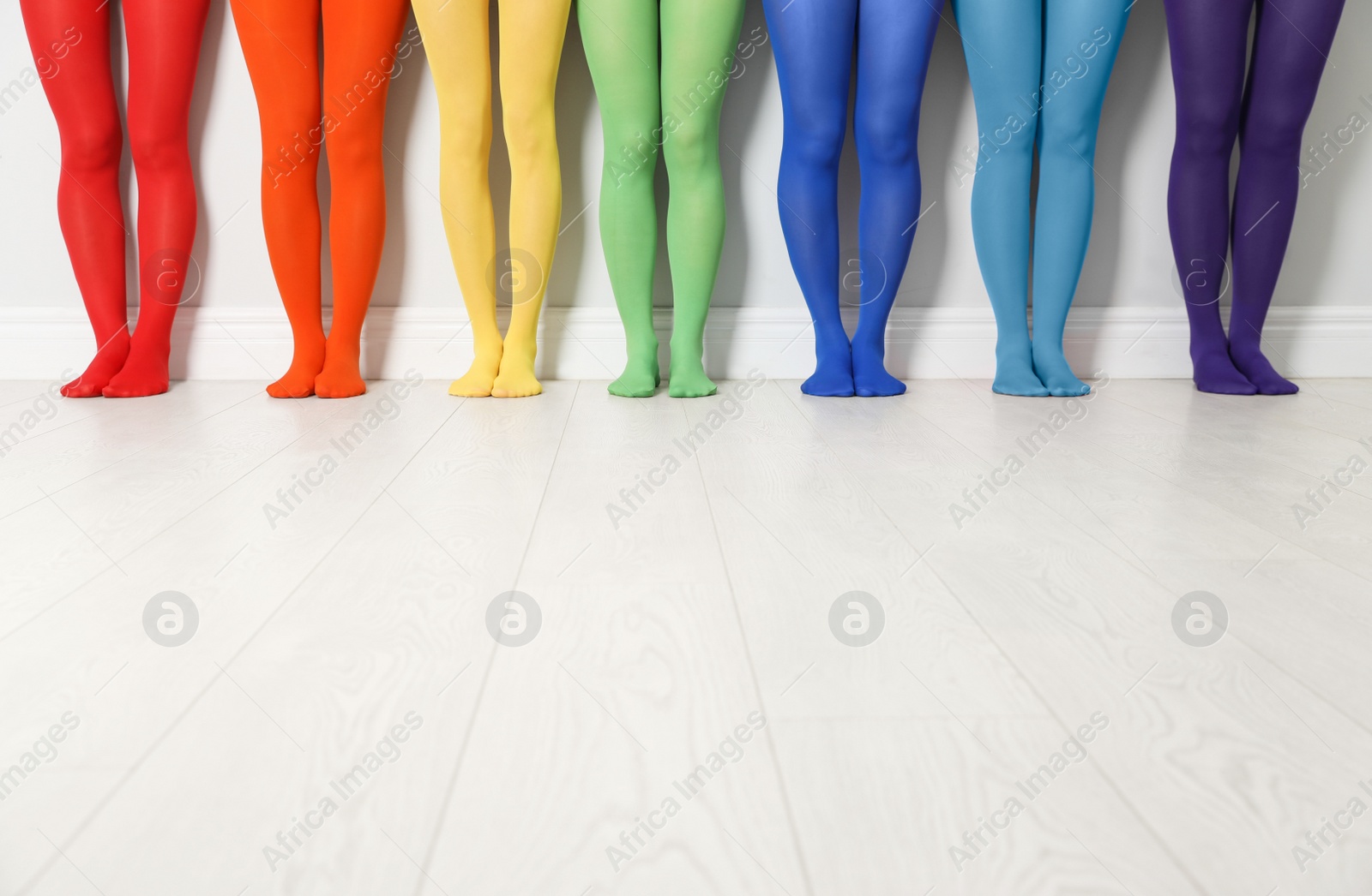 Photo of Women wearing colorful tights near white wall, closeup