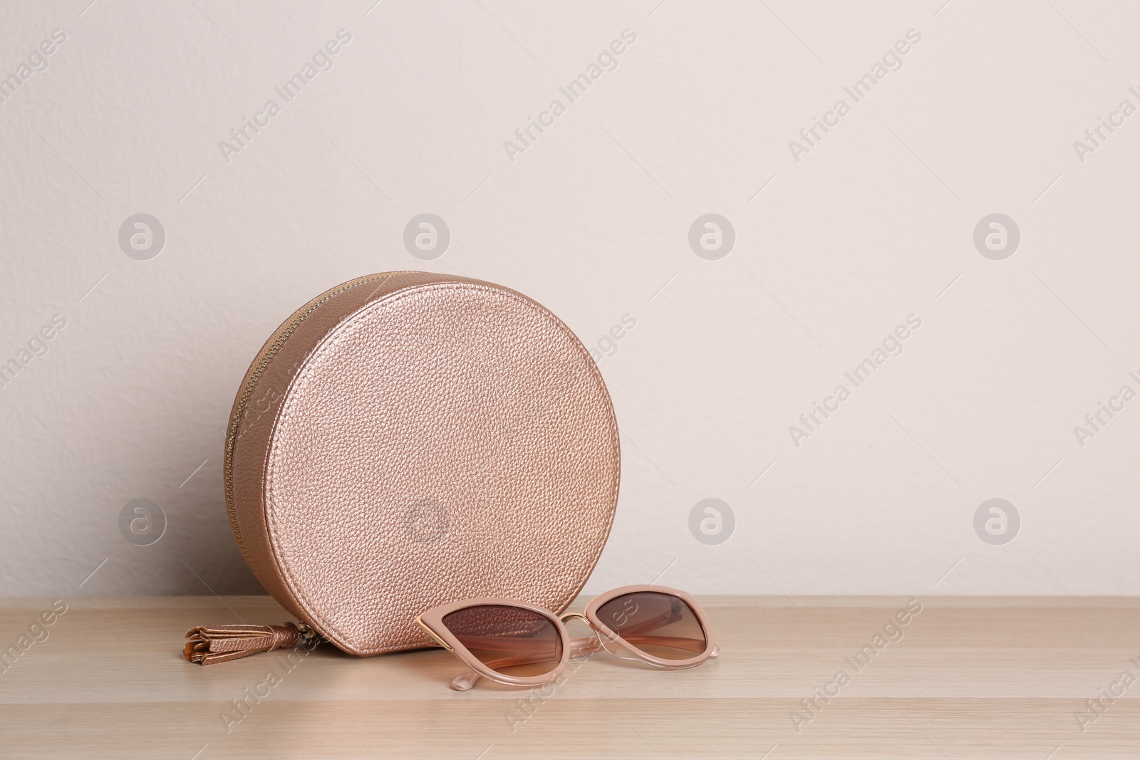 Photo of Stylish woman's bag and sunglasses on wooden table. Space for text