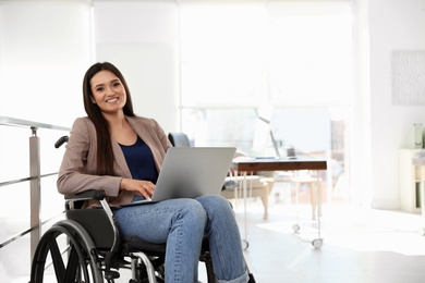 Photo of Portrait of young woman in wheelchair with laptop at office