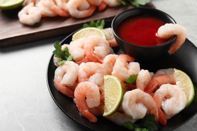 Tasty boiled shrimps with cocktail sauce, parsley and lime on light grey table, closeup