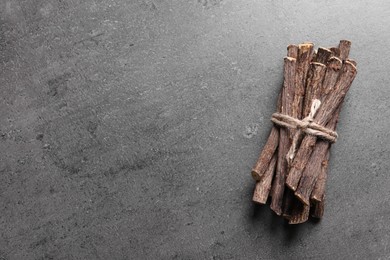 Dried sticks of liquorice root on grey table, top view. Space for text