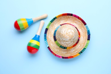 Colorful maracas and sombrero hat on light blue background, flat lay. Musical instrument