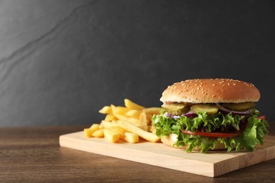 Delicious burger with beef patty and french fries on wooden table, space for text