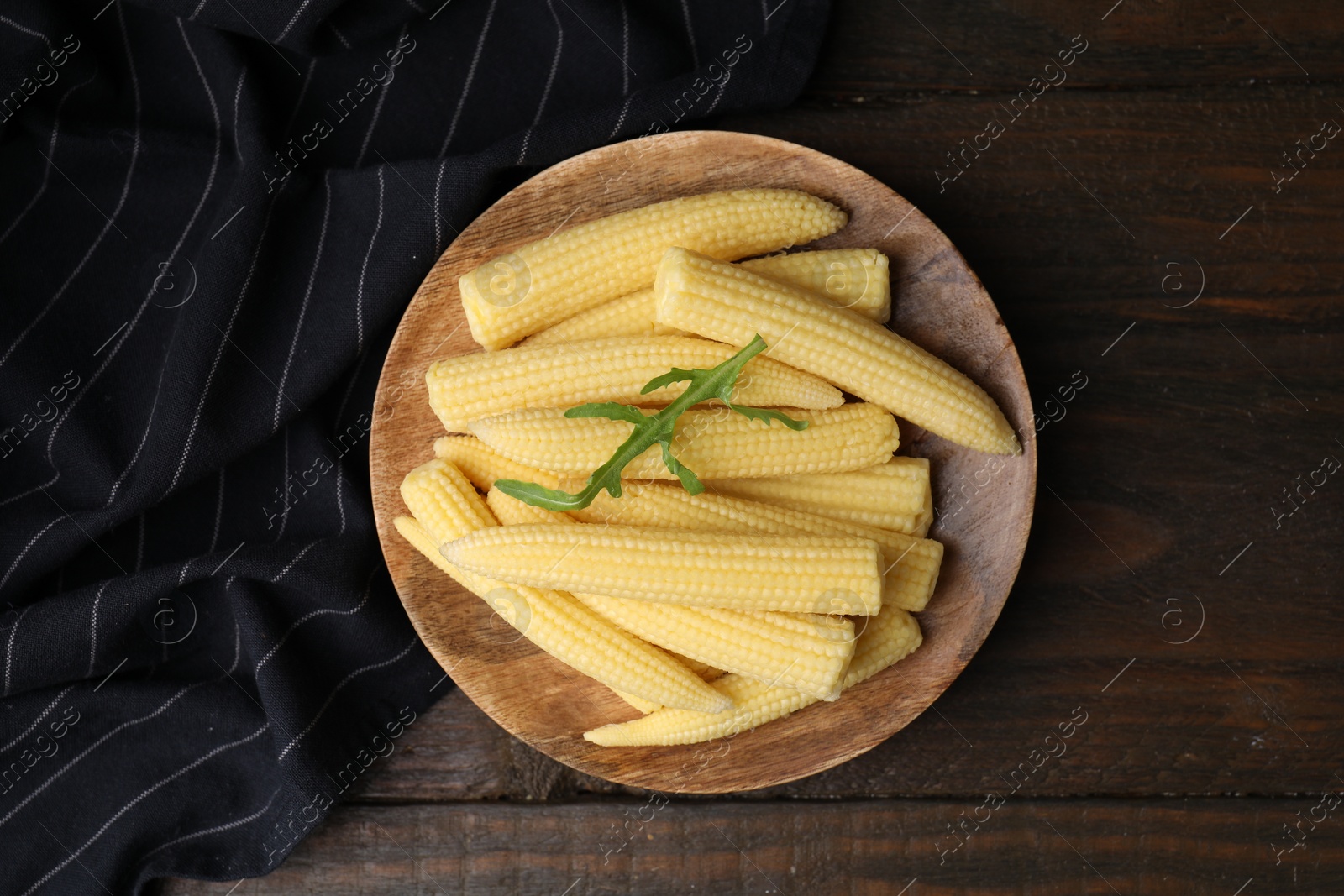 Photo of Tasty fresh yellow baby corns on wooden table, top view