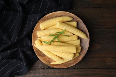 Tasty fresh yellow baby corns on wooden table, top view