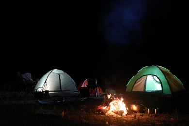 Bonfire near camping tents outdoors at night