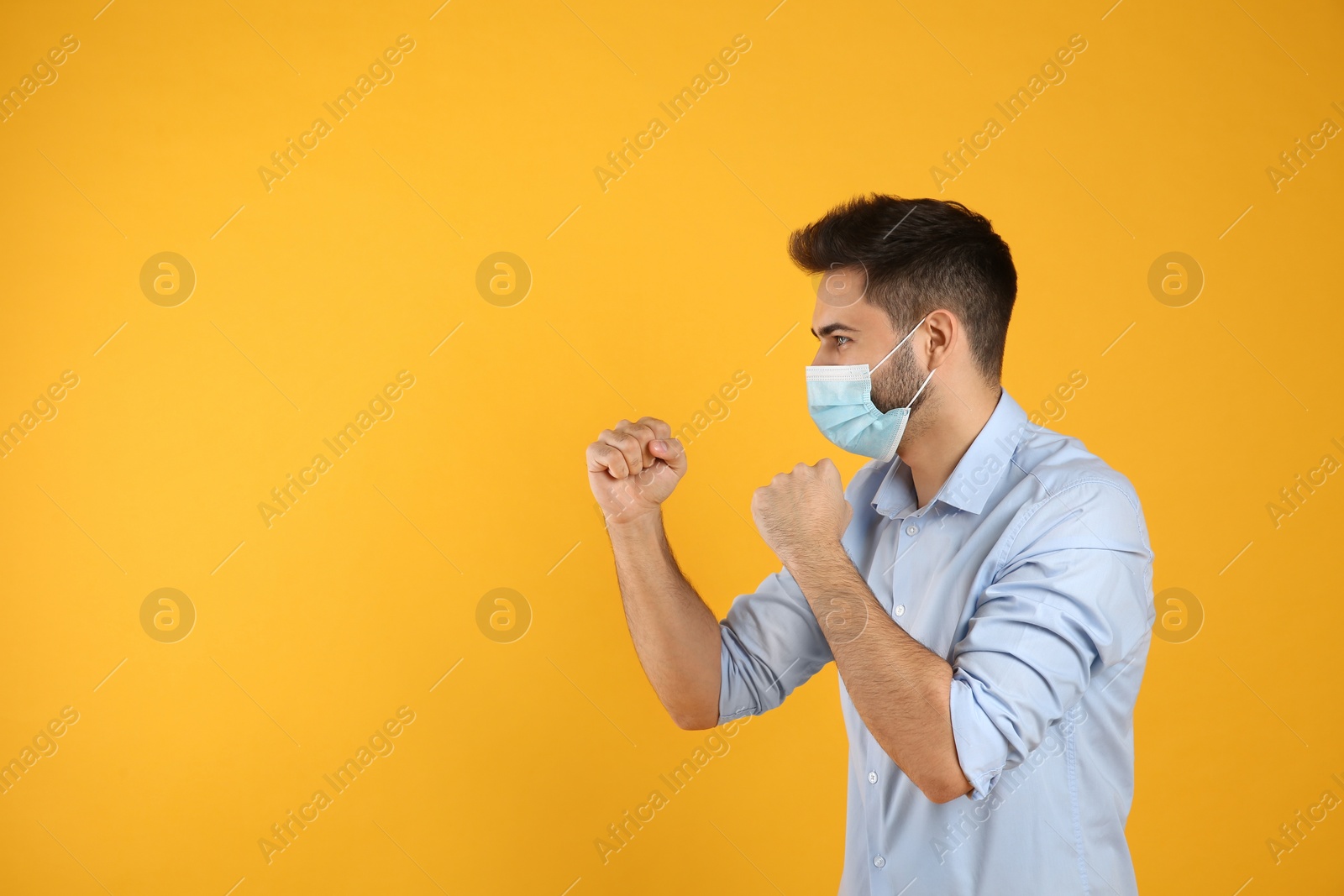 Photo of Man with protective mask in fighting pose on yellow background, space for text. Strong immunity concept