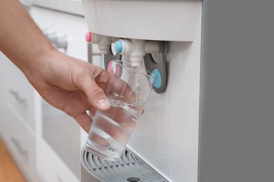 Photo of Man filling glass from water cooler, closeup