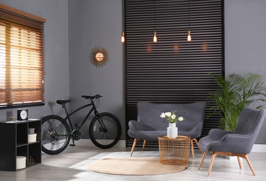 Photo of Modern bicycle and comfortable sofa in stylish living room interior