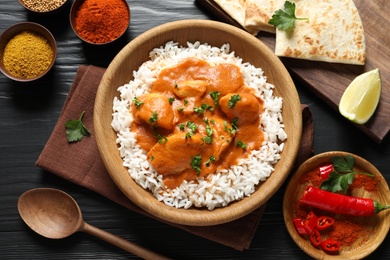 Delicious butter chicken with rice served on wooden table, flat lay