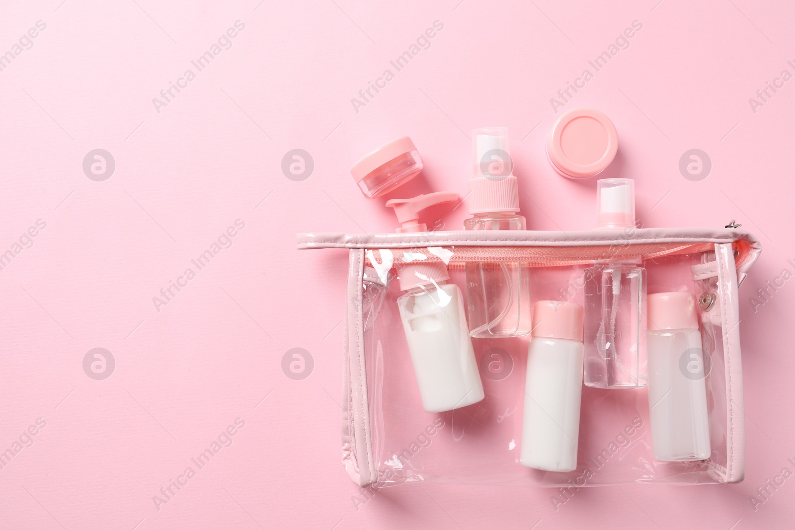 Photo of Plastic bag with cosmetic travel kit on pink background, flat lay. Space for text