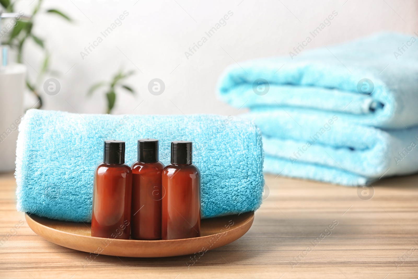 Photo of Mini bottles with cosmetic products and towels on table, space for text. Hotel amenities