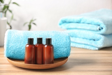 Mini bottles with cosmetic products and towels on table, space for text. Hotel amenities