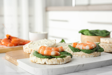 Photo of Puffed rice cakes with shrimps and basil on white marble table indoors