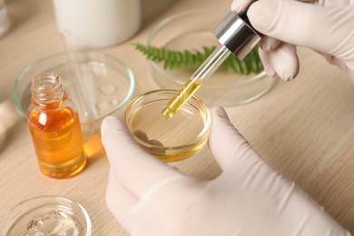 Scientist making cosmetic product at wooden table, closeup