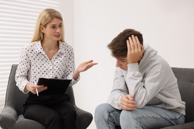 Psychologist working with teenage boy in office