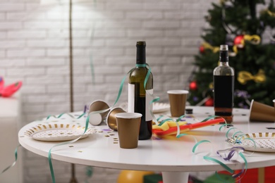 Photo of Messy table with cups and bottles indoors. Chaos after party