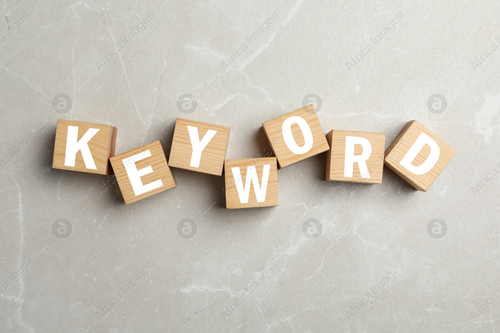 Photo of Word KEYWORD made of wooden cubes on marble background, flat lay