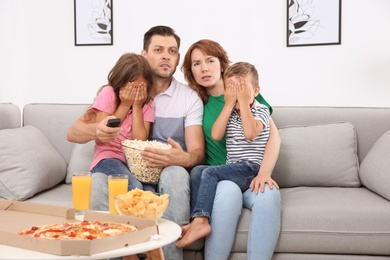 Family watching TV with popcorn in room