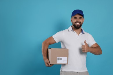 Photo of Courier holding cardboard box on light blue background, space for text