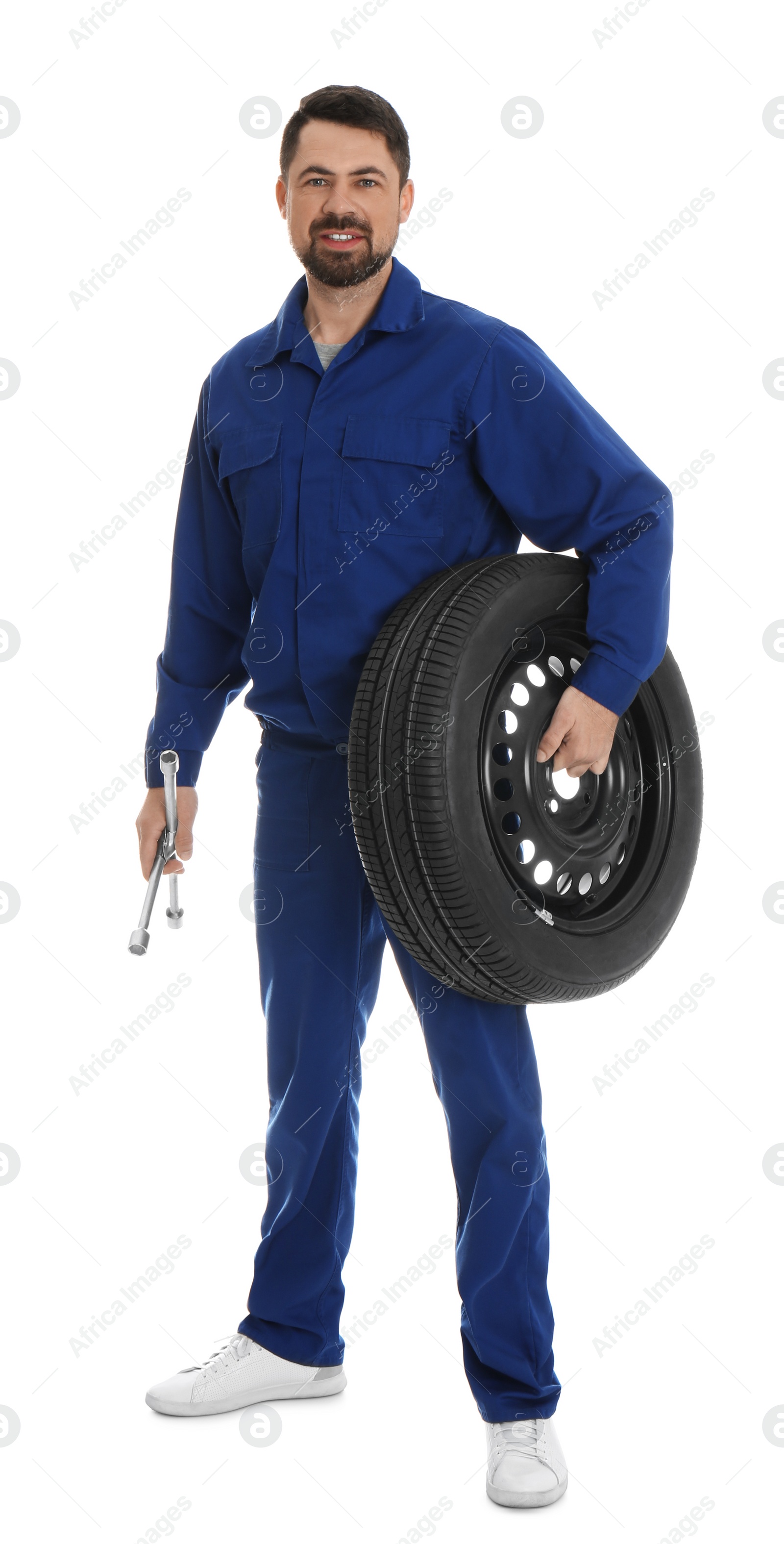 Photo of Full length portrait of professional auto mechanic with lug wrench and wheel on white background