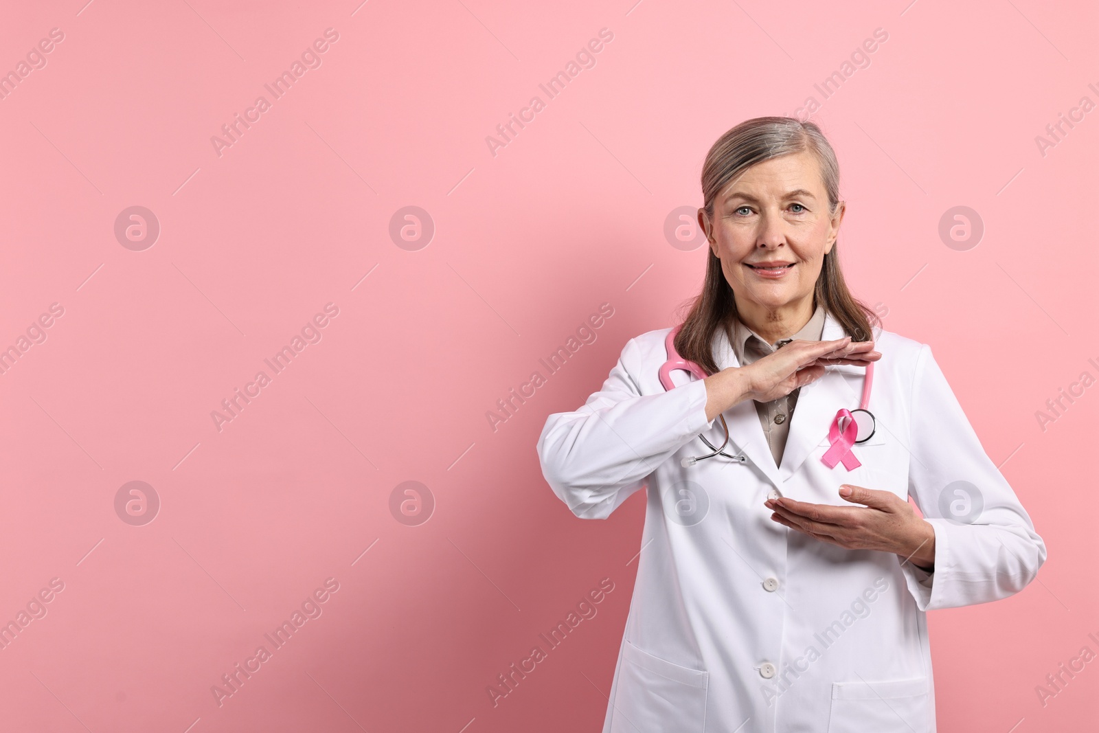 Photo of Mammologist with pink ribbon on color background, space for text. Breast cancer awareness
