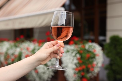 Photo of Woman holding glass of rose wine outdoors, closeup