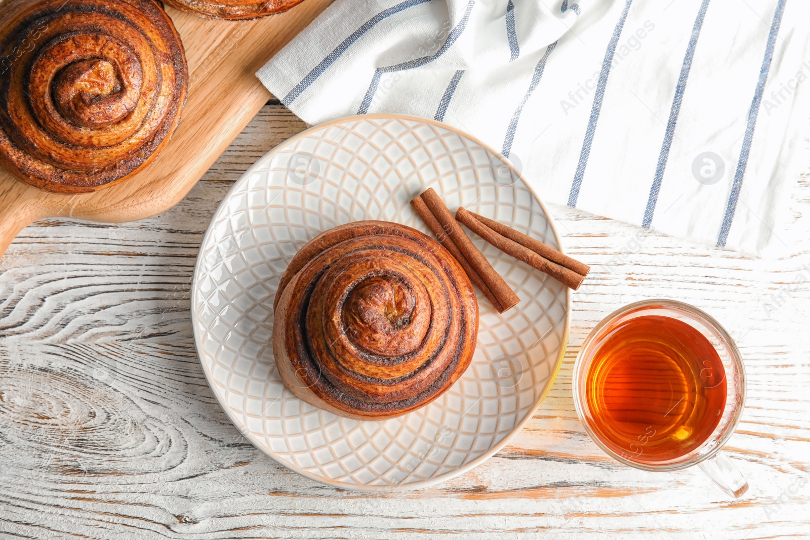 Photo of Flat lay composition with freshly baked cinnamon roll on white wooden background