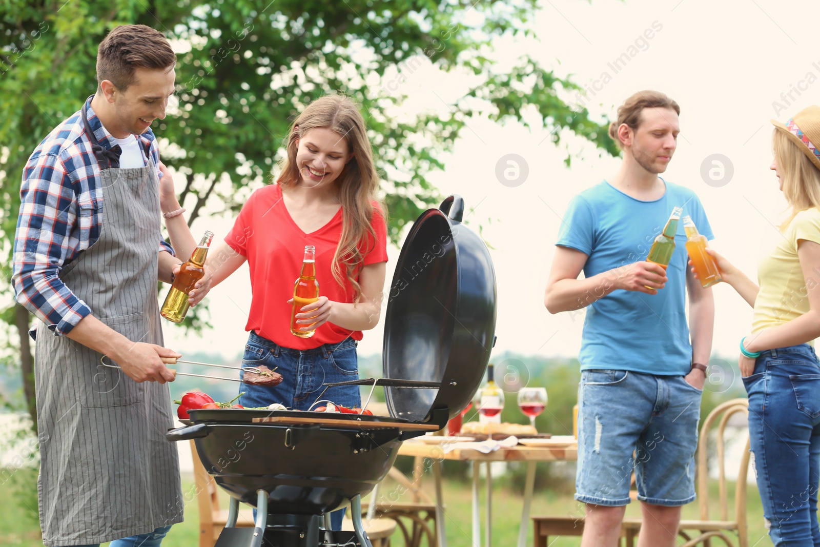 Photo of Young people having barbecue with modern grill outdoors