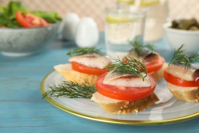 Delicious sandwiches with salted herring, tomatoes and dill on light blue wooden table, closeup