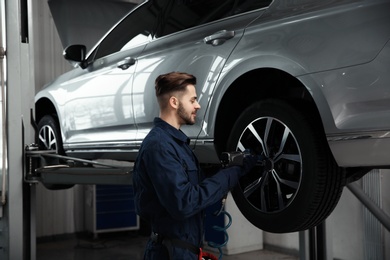 Technician working with car in automobile repair shop