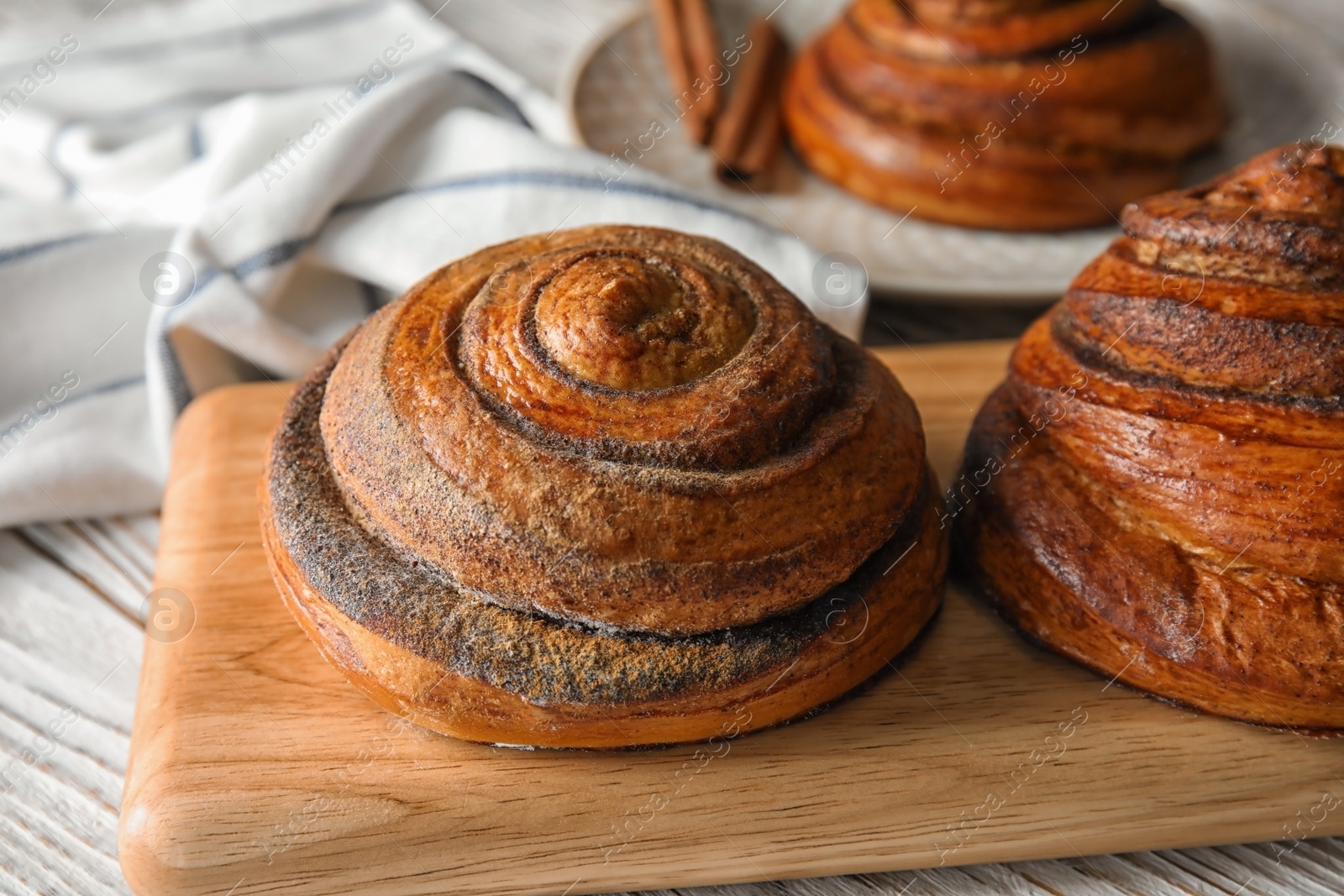 Photo of Wooden board with cinnamon rolls on table, closeup