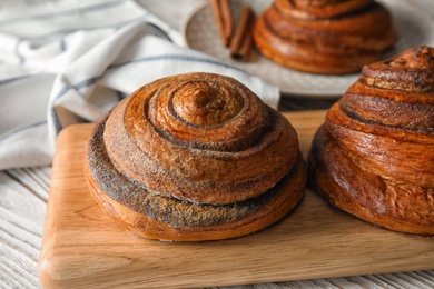 Wooden board with cinnamon rolls on table, closeup