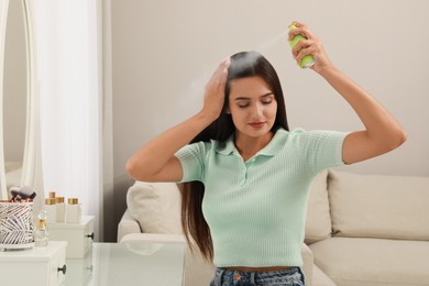 Photo of Woman applying dry shampoo onto her hair at home