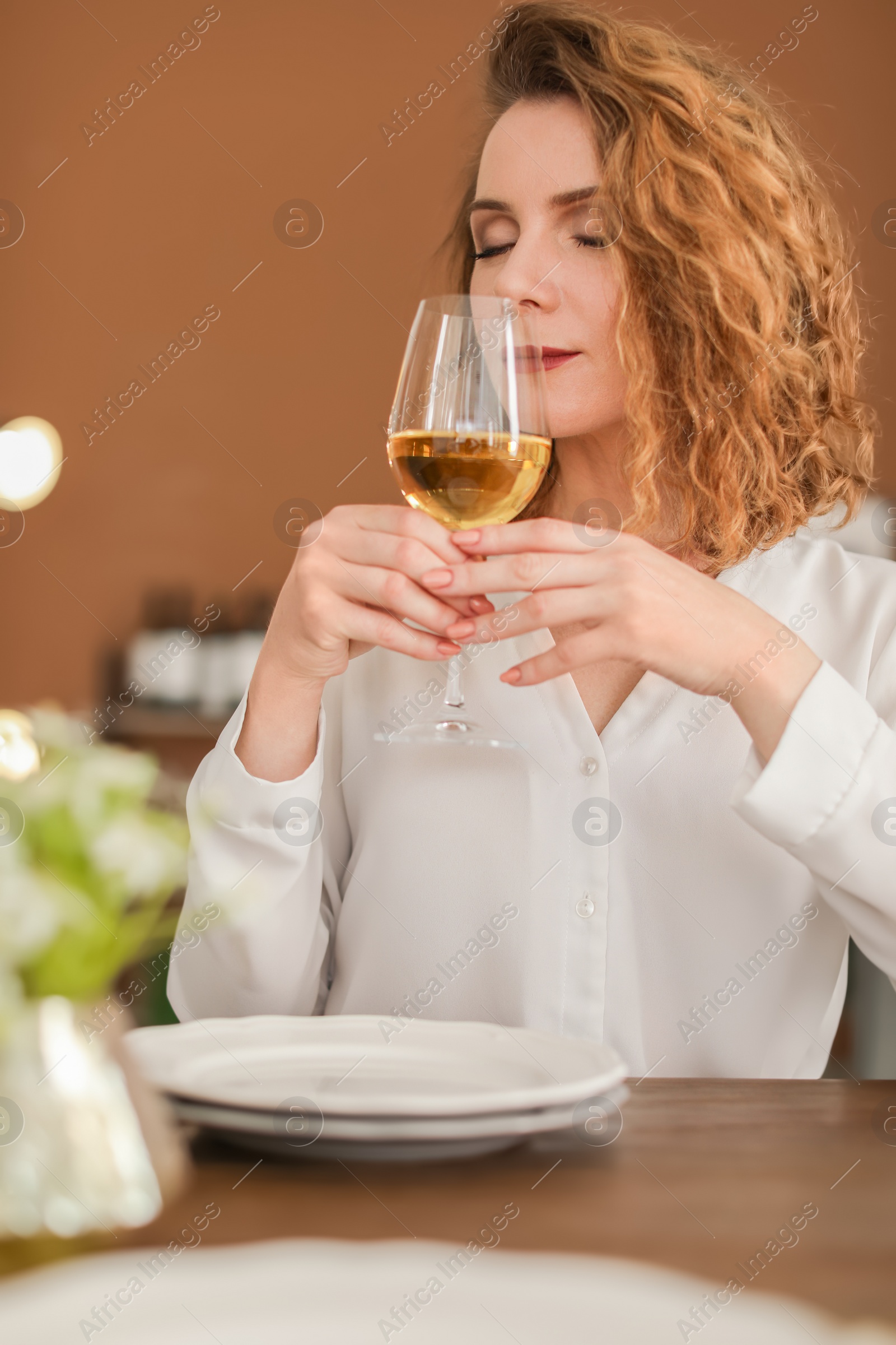 Photo of Woman with glass of wine at table in restaurant