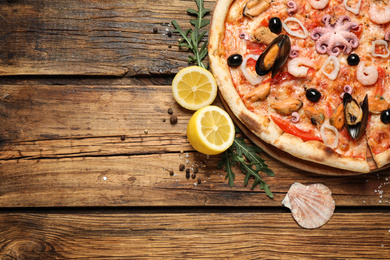 Delicious seafood pizza on wooden table, flat lay. Space for text