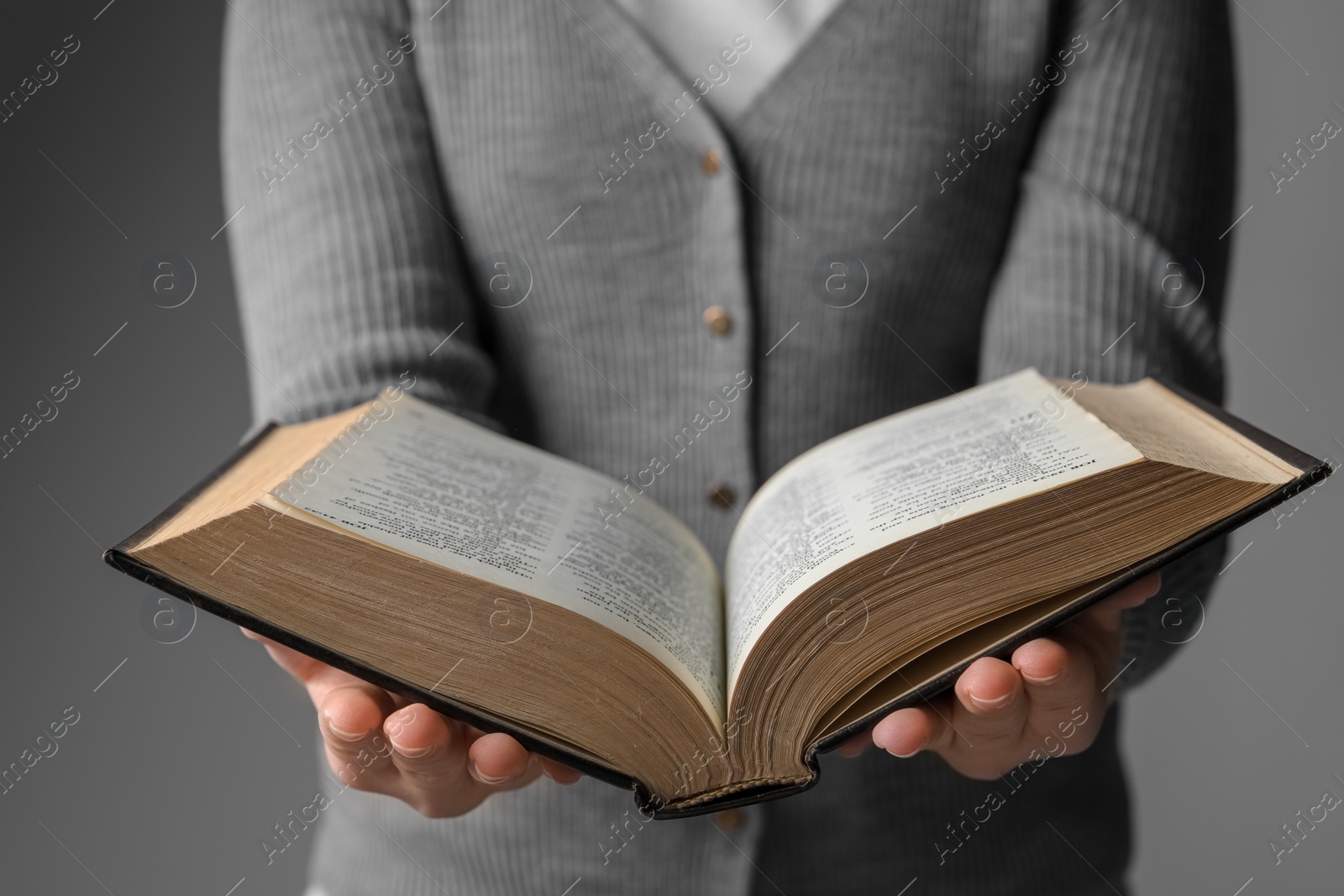 Photo of Woman reading Bible against grey background, closeup